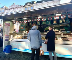 Two ENPICOM employees in front of a seafood market stall in 's-Hertogenbosch.